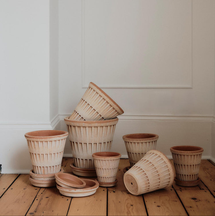 Stack of bergs potter pots on a wooden floor against a white wall