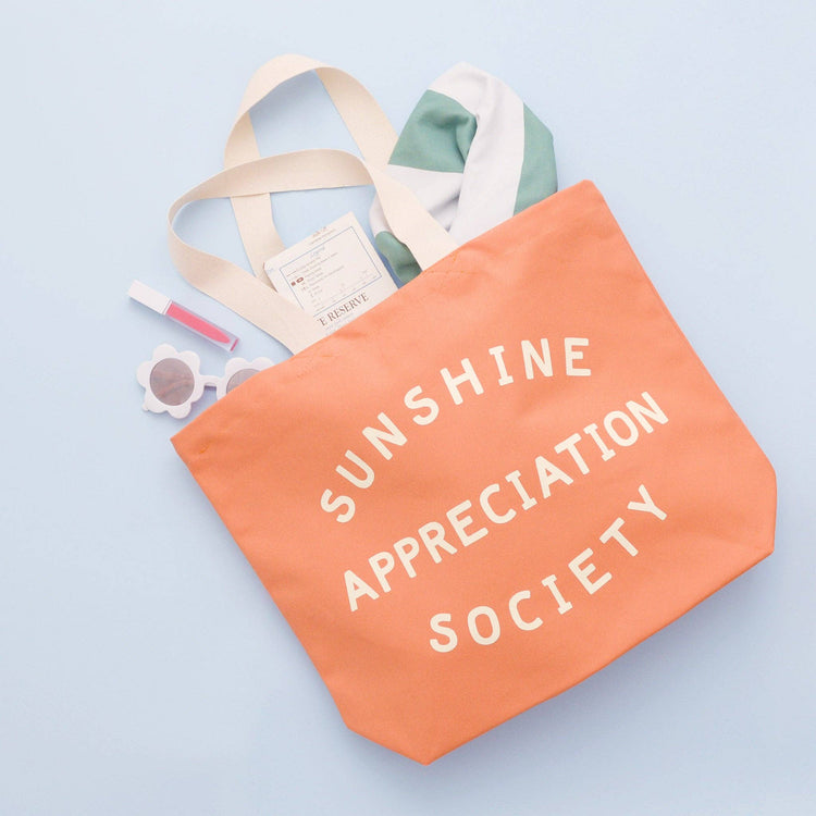 Peach Canvas Tote Bag with ‘Sunshine Appreciation Society’ text on a Blue Background