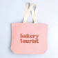 Blush Pink Tote Bag with ‘Bakery Tourist ’ text on a Blue Background