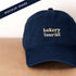 Navy Cotton Baseball Cap with ‘Bakery Tourist’ Text on a Neutral Background