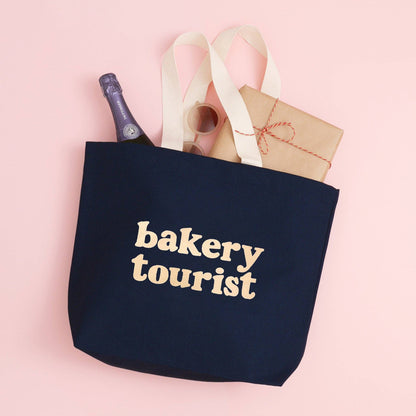 Midnight Blue Tote Bag with ‘Bakery Tourist’ Text on a Pink Background