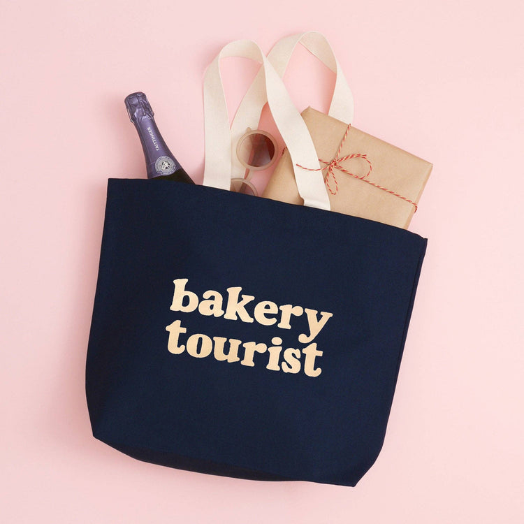 Midnight Blue Tote Bag with ‘Bakery Tourist’ Text on a Pink Background