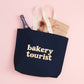 Midnight Blue Tote Bag with ‘Bakery Tourist’ Text on a Pink Background