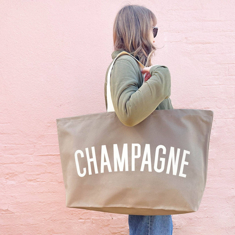 Person holding a beige tote bag with &