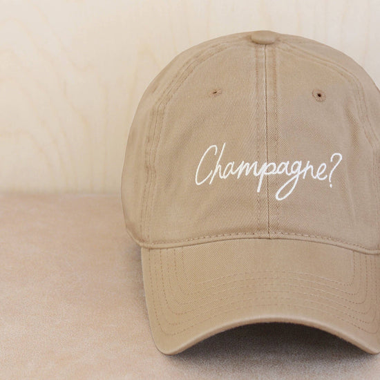 Cotton Baseball Cap with ‘Champagne?’ Text on a Neutral Background