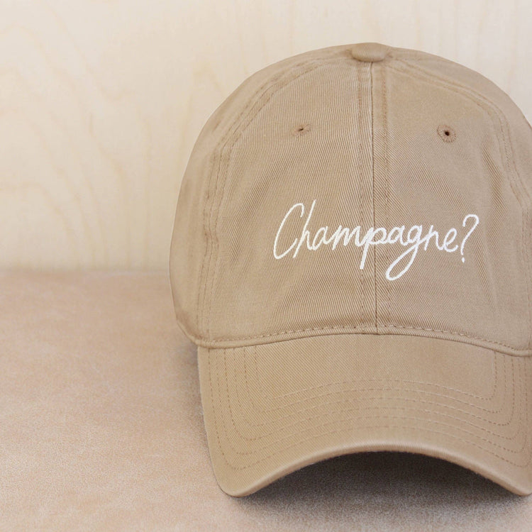 Cotton Baseball Cap with ‘Champagne?’ Text on a Neutral Background