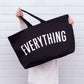 Person holding a black bag with &