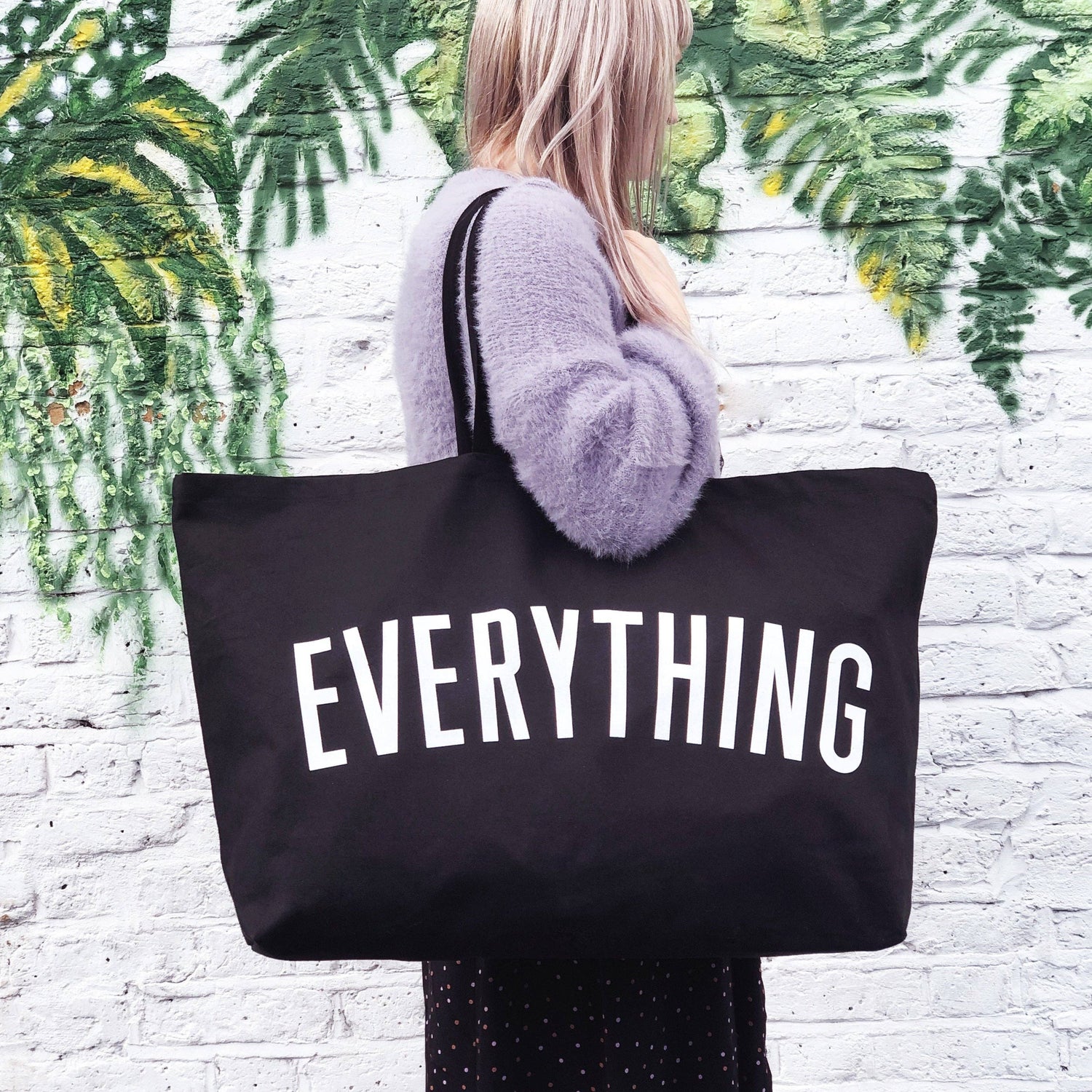 Person holding a black tote bag with &
