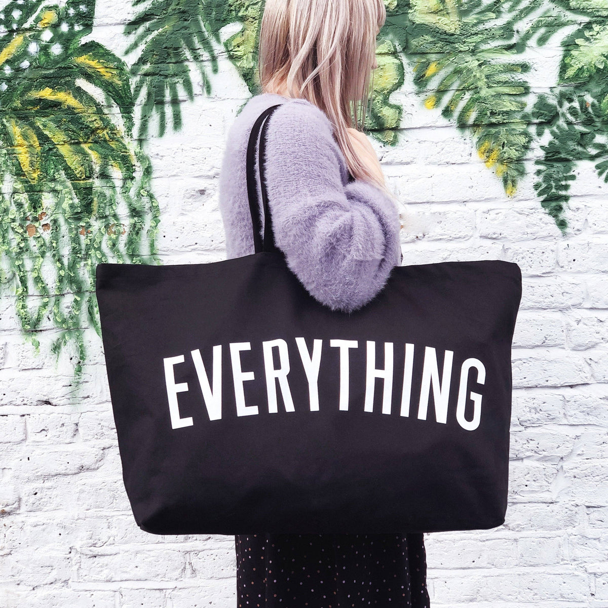 Person holding a black tote bag with &