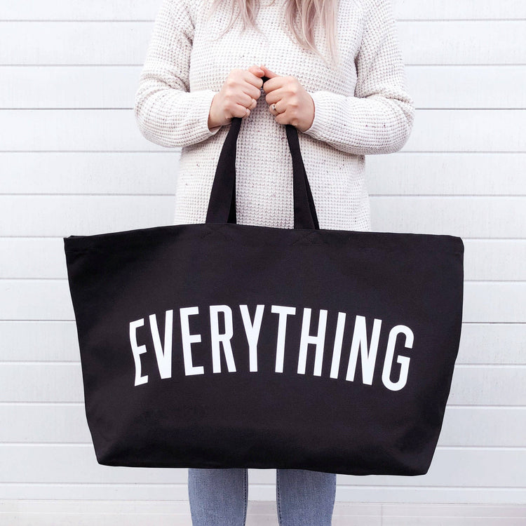 Person holding a black tote bag with &