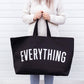 Person holding a black tote bag with &