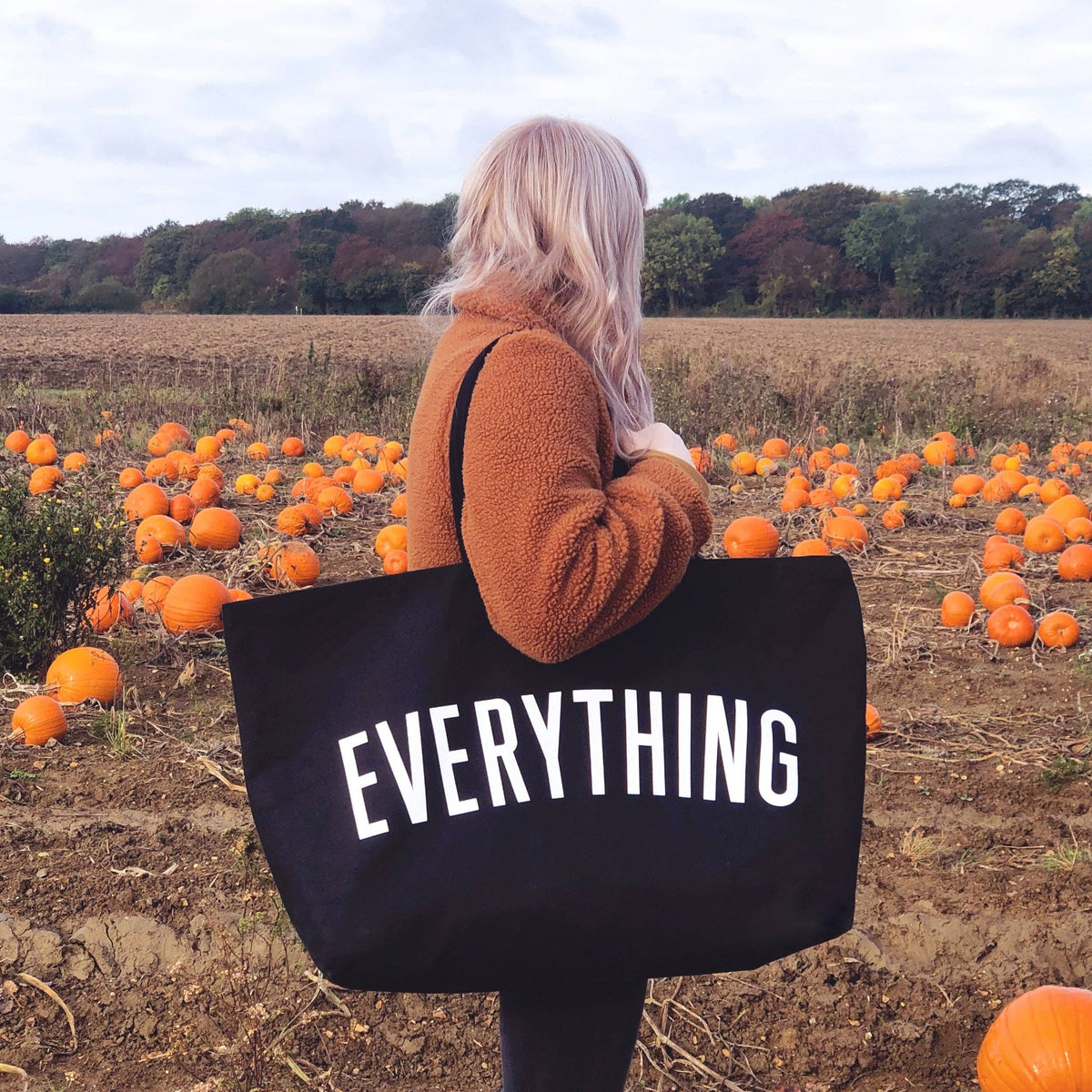 Person holding a black tote bag with &