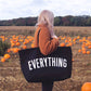 Person holding a black tote bag with &