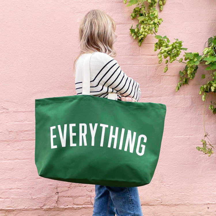 Person holding a green tote bag with &