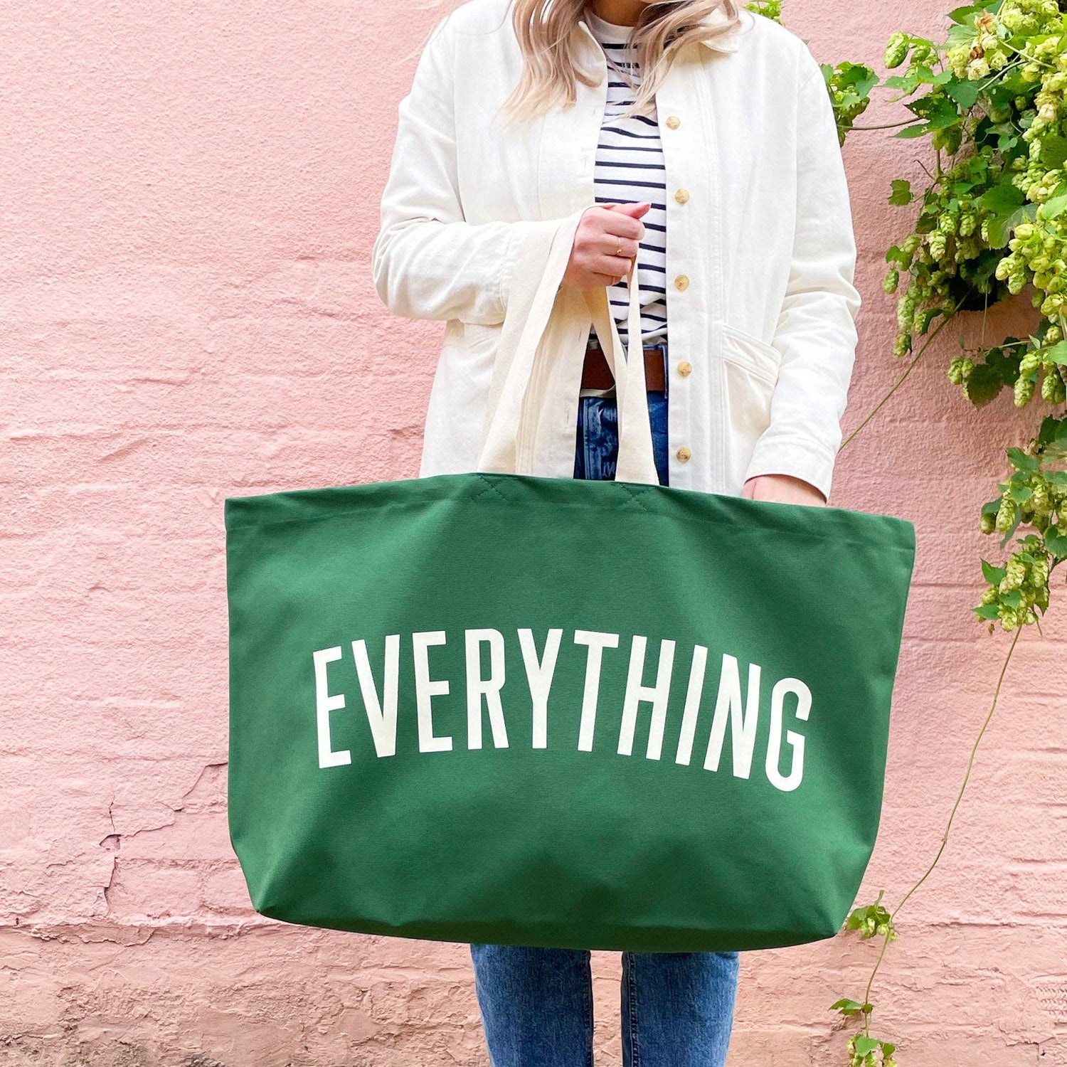 Person holding a green tote bag with &