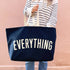Person holding a navy tote bag with &