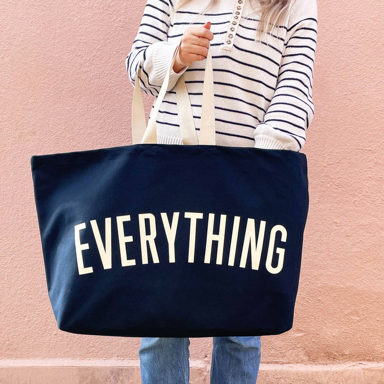 Person holding a navy tote bag with &
