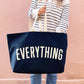 Person holding a navy tote bag with &