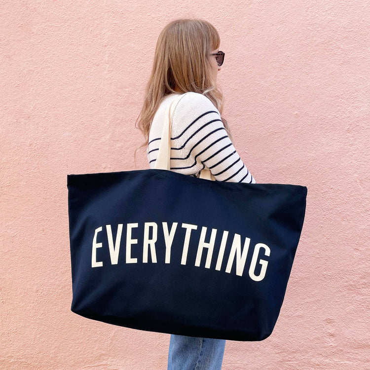 Person holding a navy tote bag with &