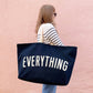 Person holding a navy tote bag with &