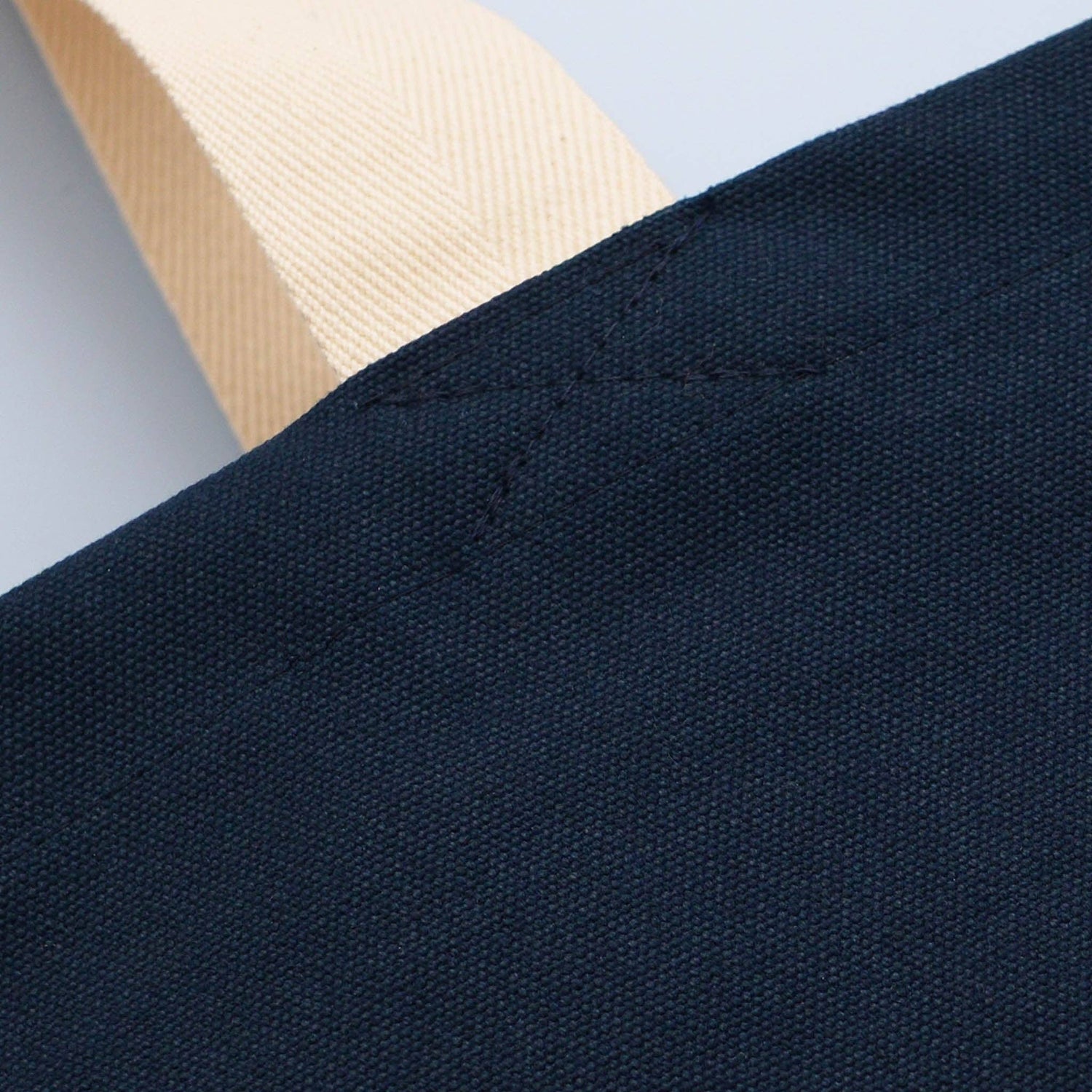 Close-up of dark blue fabric with a beige strap in the background