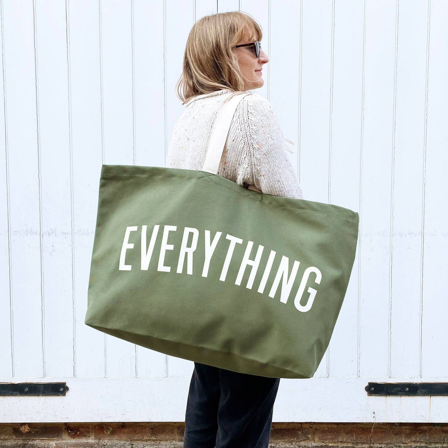 Person holding a green tote bag with &