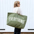 Person holding a green tote bag with &