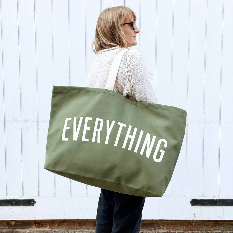 Person holding a green tote bag with &