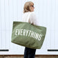 Person holding a green tote bag with &