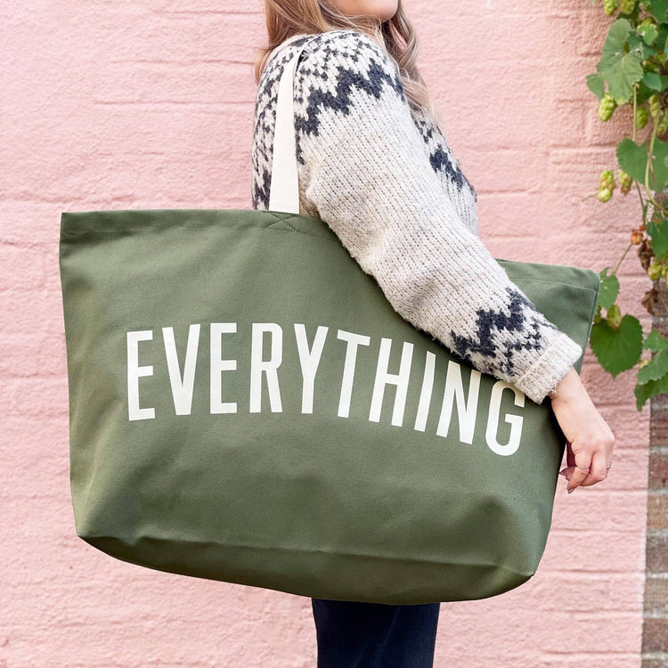 Person holding a green tote bag with &