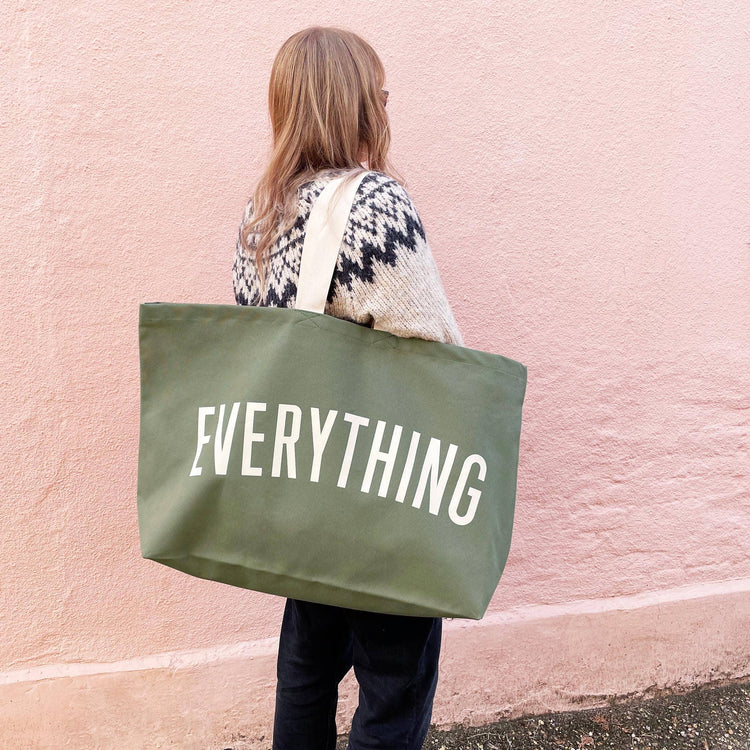Person holding a green tote bag with &