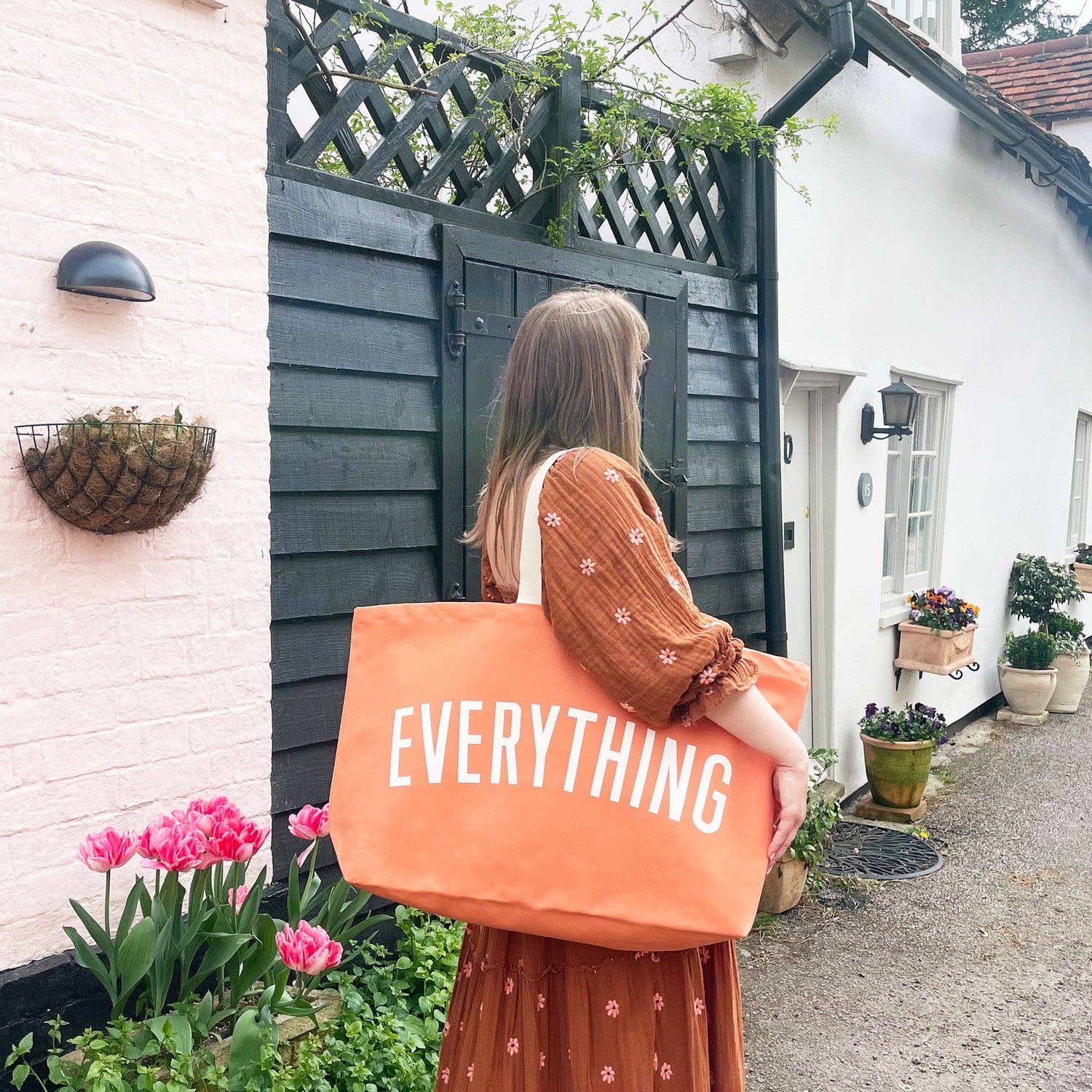 Woman holding an orange tote bag with &