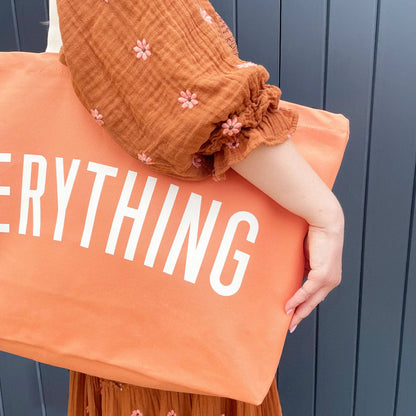 Person holding an orange pillow with &