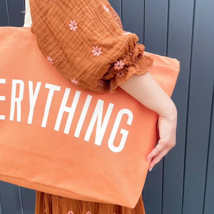 Person holding an orange pillow with &