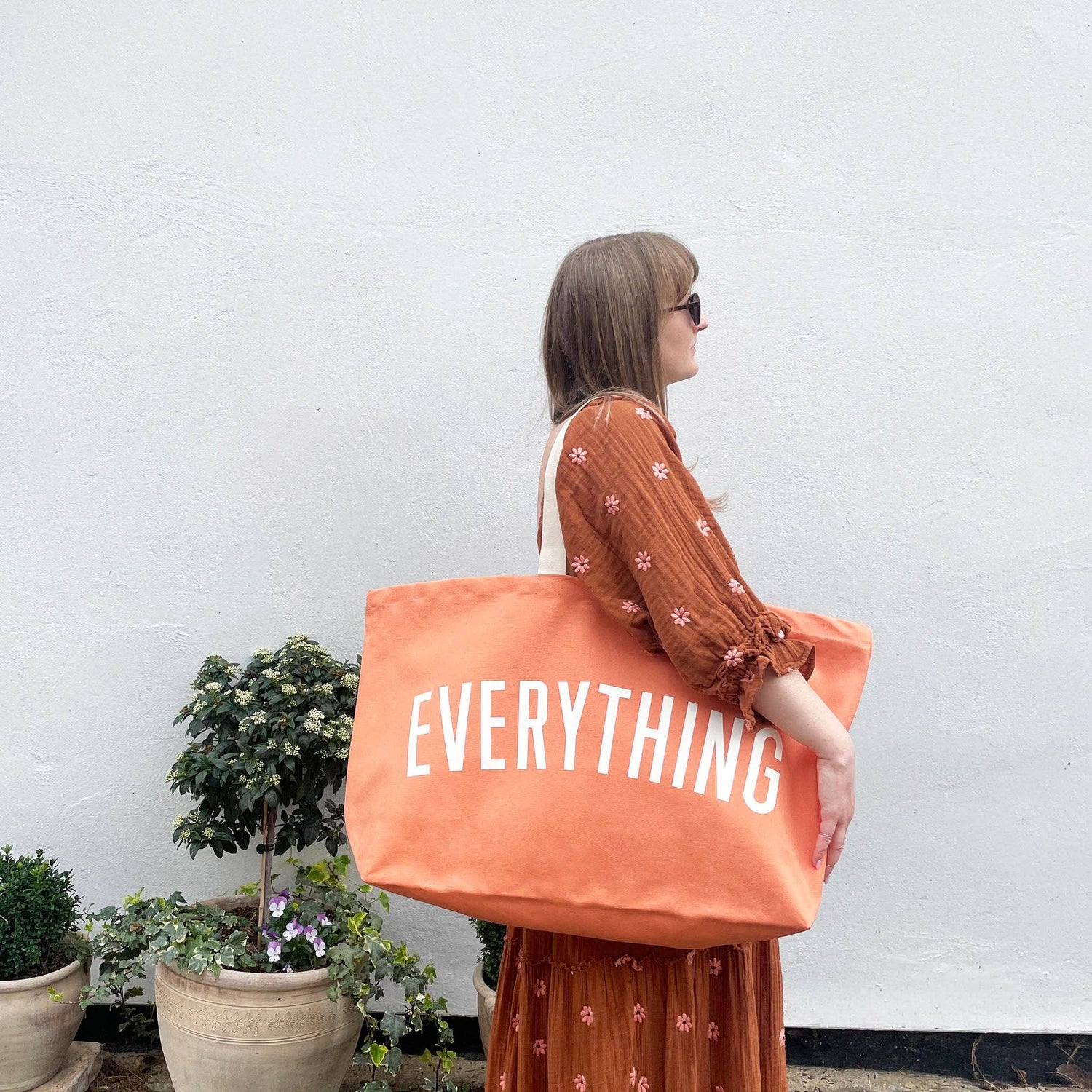 Woman holding an orange tote bag with &