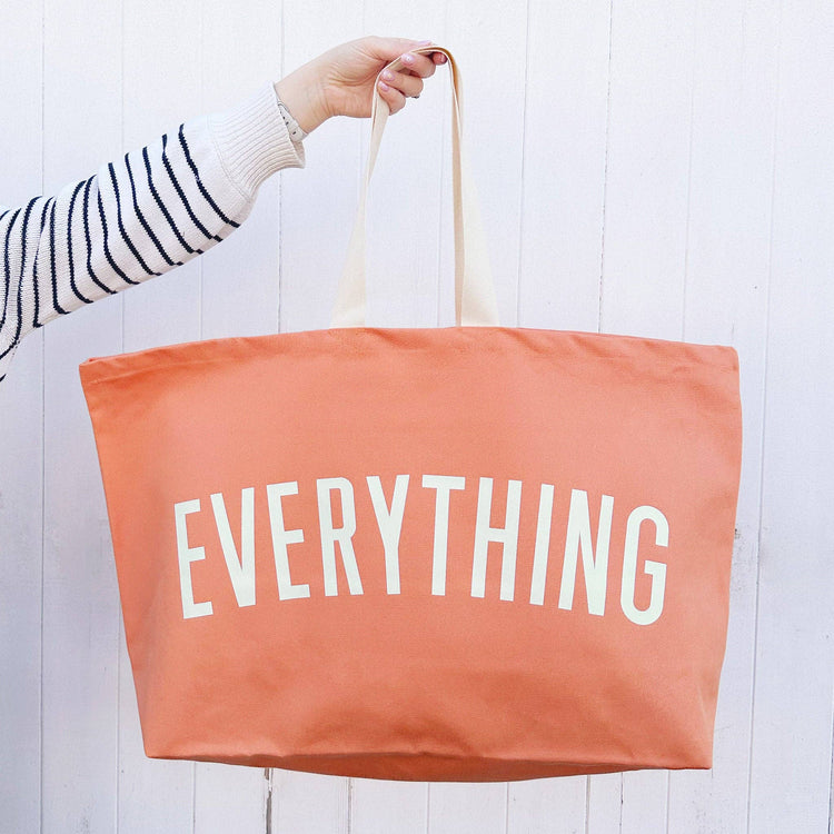 Person holding a peach-colored tote bag with &