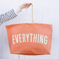 Person holding a peach-colored tote bag with &