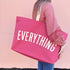 Person Carrying a Bright Pink Really Big Bag with ‘Everything’ Text on a Pink Background