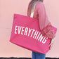 Person Carrying a Bright Pink Really Big Bag with ‘Everything’ Text on a Pink Background