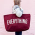 Person Carrying a Burgundy Really Big Bag with ‘Everything’ Text on a Pink Background