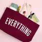 Person Carrying a Burgundy Really Big Bag with ‘Everything’ Text on a Pink Background