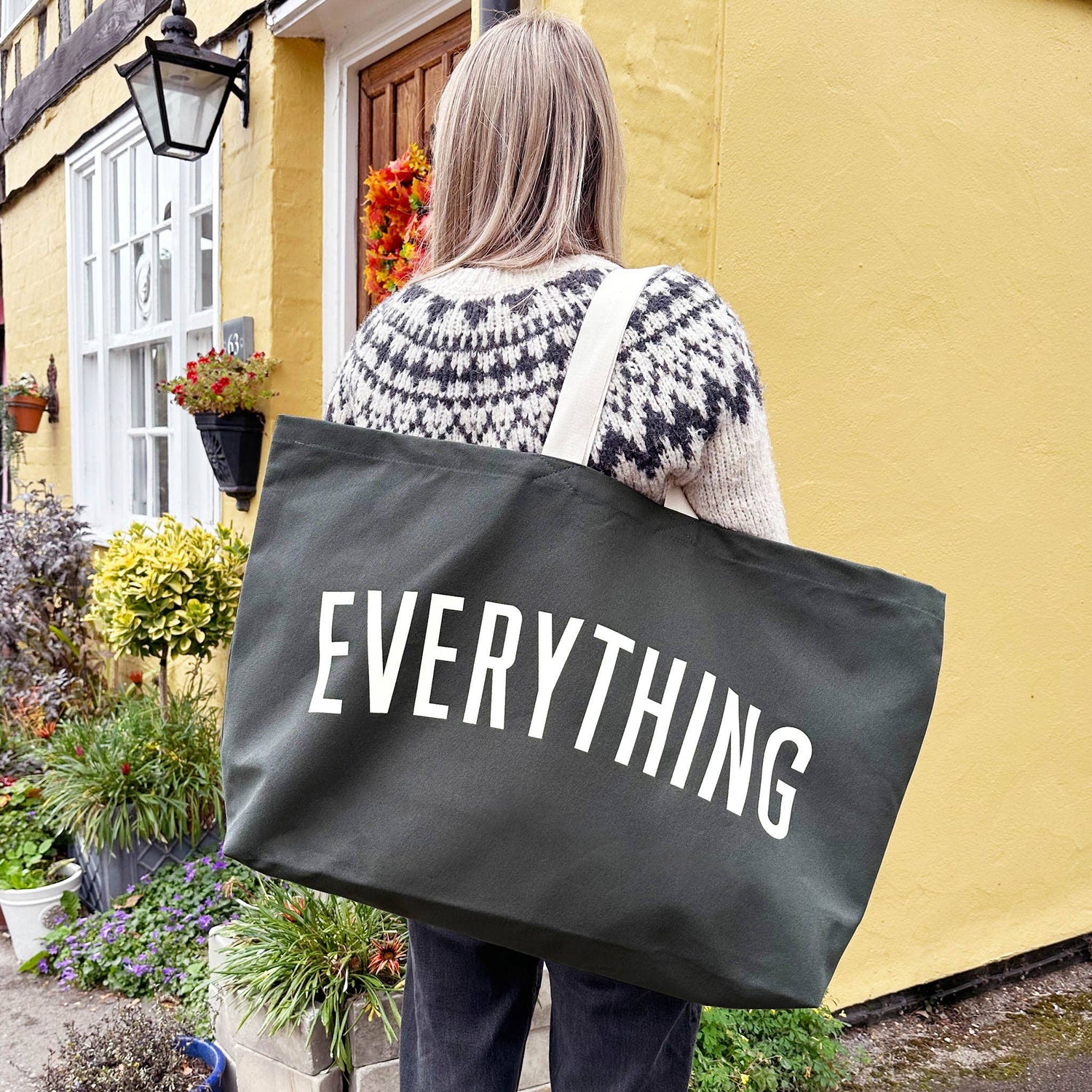 Person Carrying a Grey Really Big Bag with ‘Everything’ Text on a Mixed Background