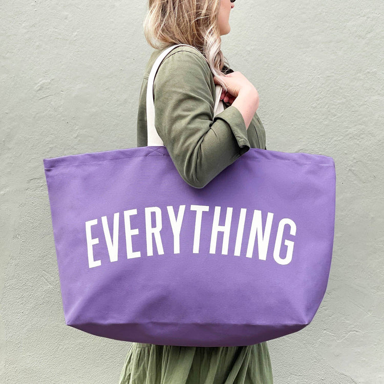 Person Carrying a Lavender Really Big Bag with ‘Everything’ Text on a Whitw  Background