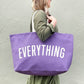 Person Carrying a Lavender Really Big Bag with ‘Everything’ Text on a Whitw  Background