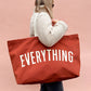 Person Carrying a Rust Really Big Bag with ‘Everything’ Text on a Pink Background