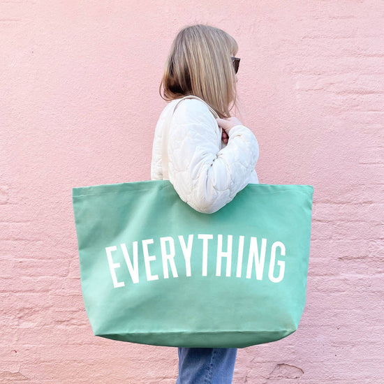 Person Carrying a Sea Glass Really Big Bag with ‘Everything’ Text on a Pink Background