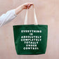 Green tote bag with motivational text held by a person against a beige background