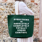 Person holding a green tote bag with text against a stone wall background