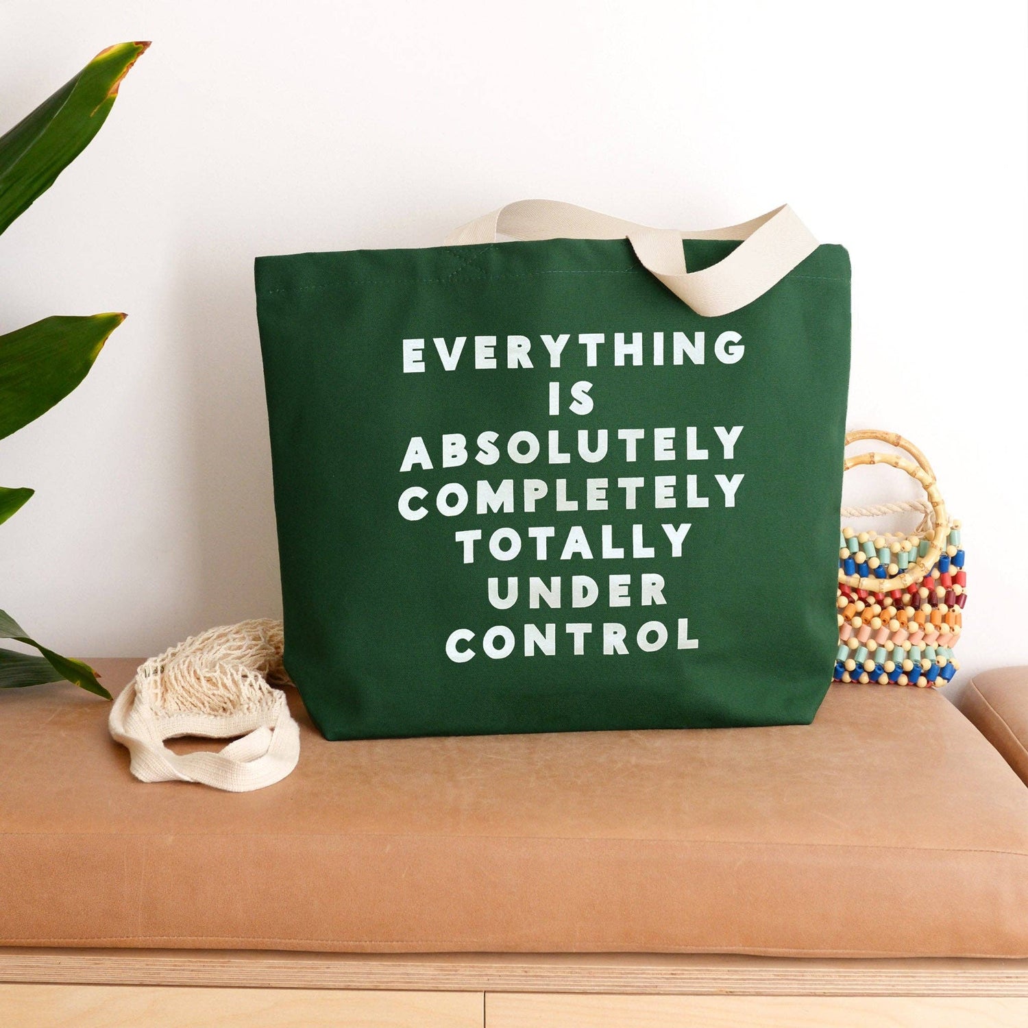 Green tote bag with motivational quote on a wooden surface with decorative elements.