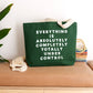 Green tote bag with motivational quote on a wooden surface with decorative elements.